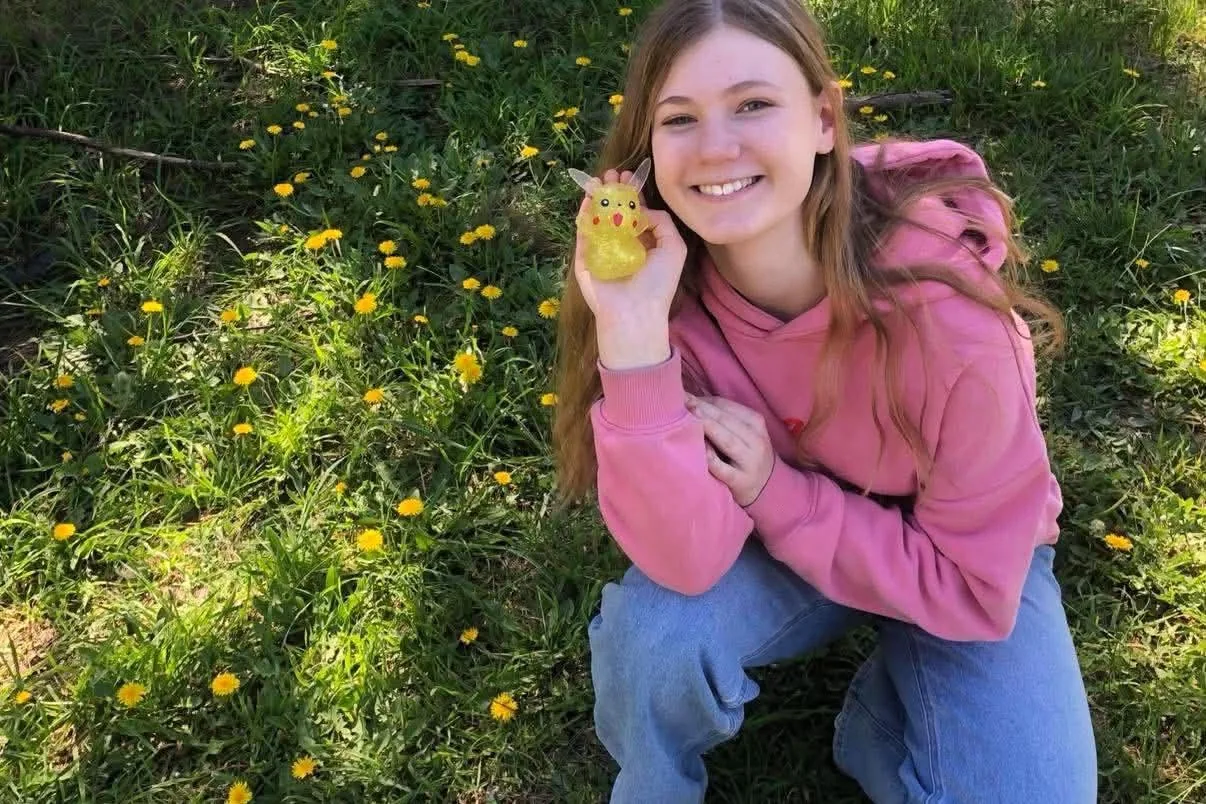 Isabelle smiling outdoors while holding a small yellow toy