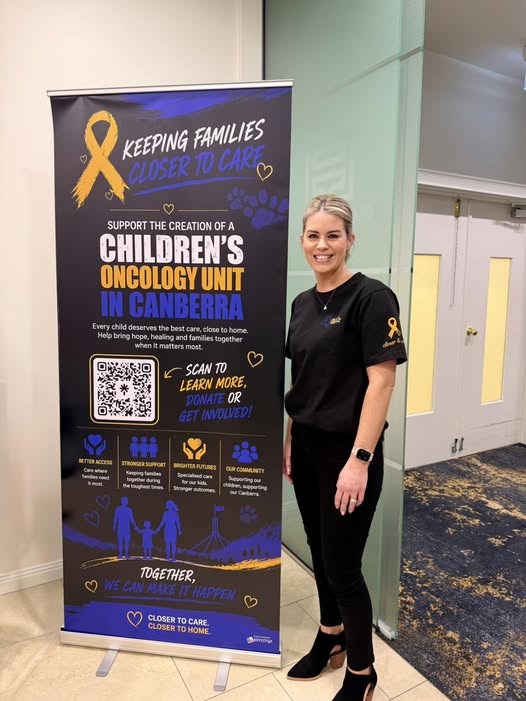 Robyn, founder of Closer 2 Care, standing beside a Closer 2 Care campaign banner.